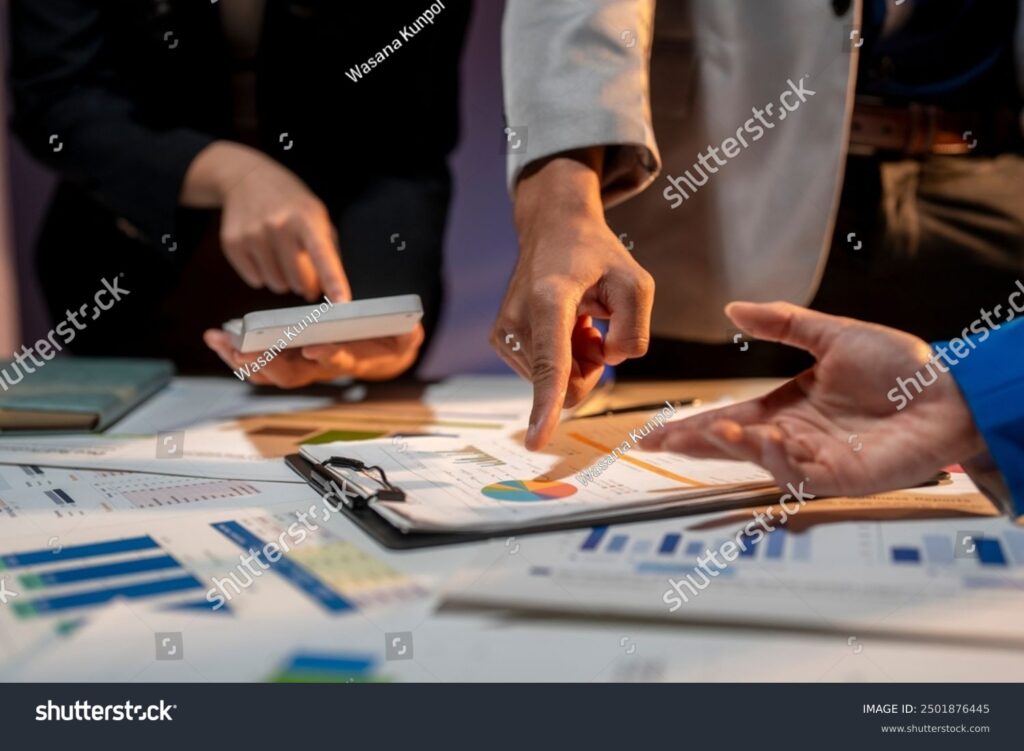 stock-photo-three-people-are-looking-at-a-table-with-a-lot-of-papers-and-a-calculator-they-are-pointing-at-a-2501876445